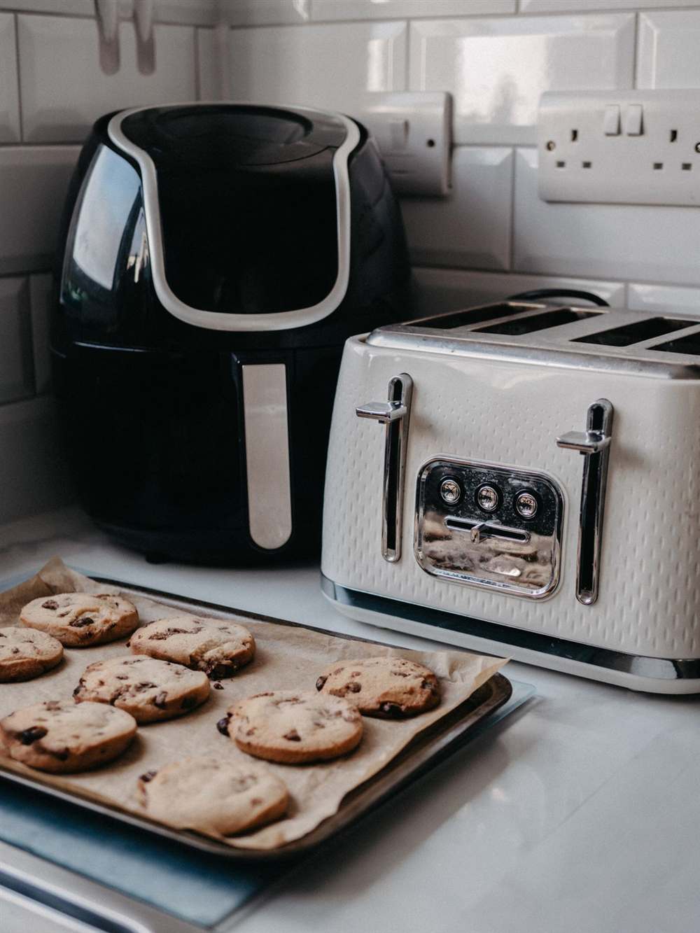 Air fryer compacta negra junto a una tostadora en una encimera pequeña