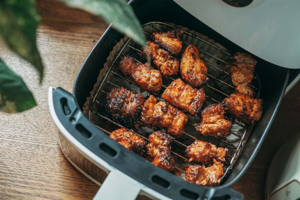 Pollo cocinado en la cesta de una air fryer compacta