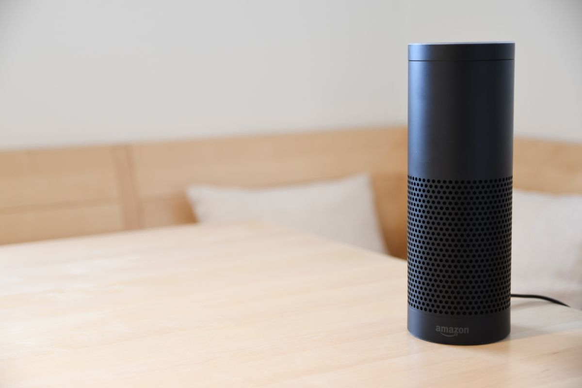 Altavoz inteligente Amazon Echo negro sobre una mesa de madera en un salón