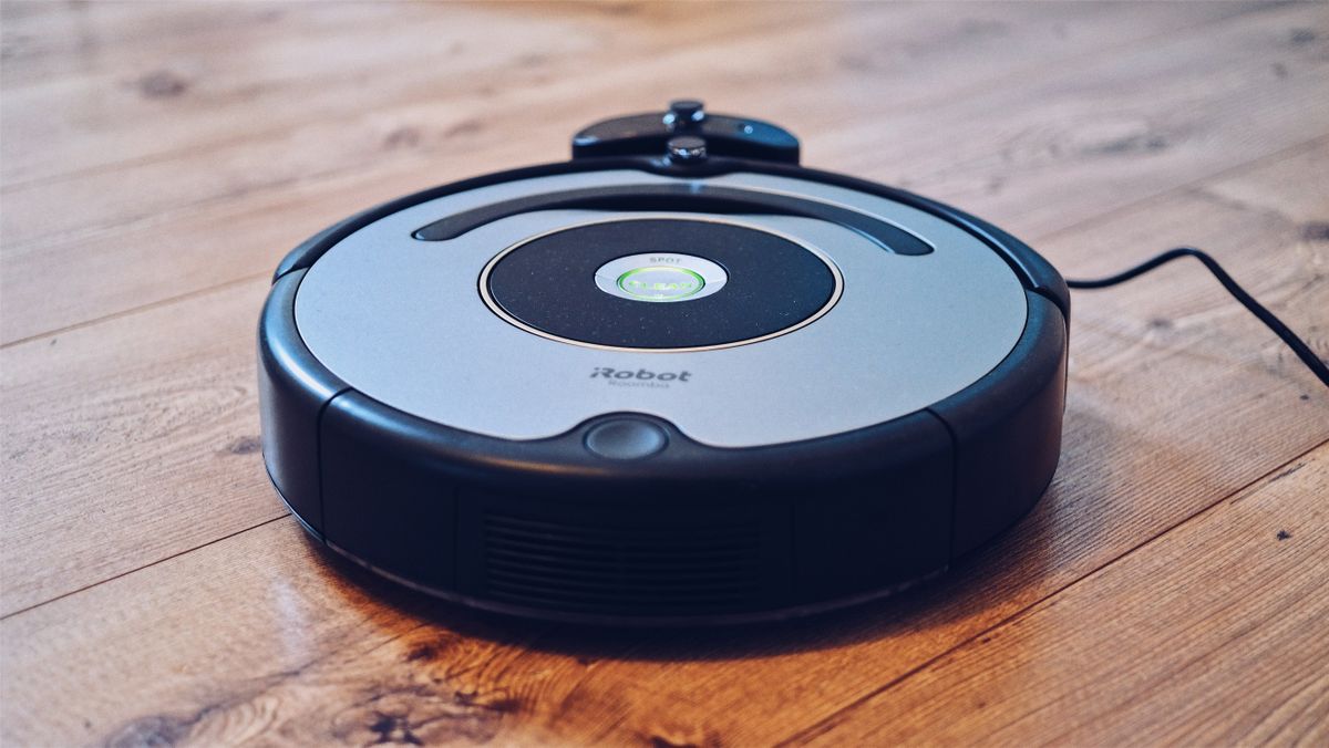 Robot aspirador redondo sobre suelo de madera
