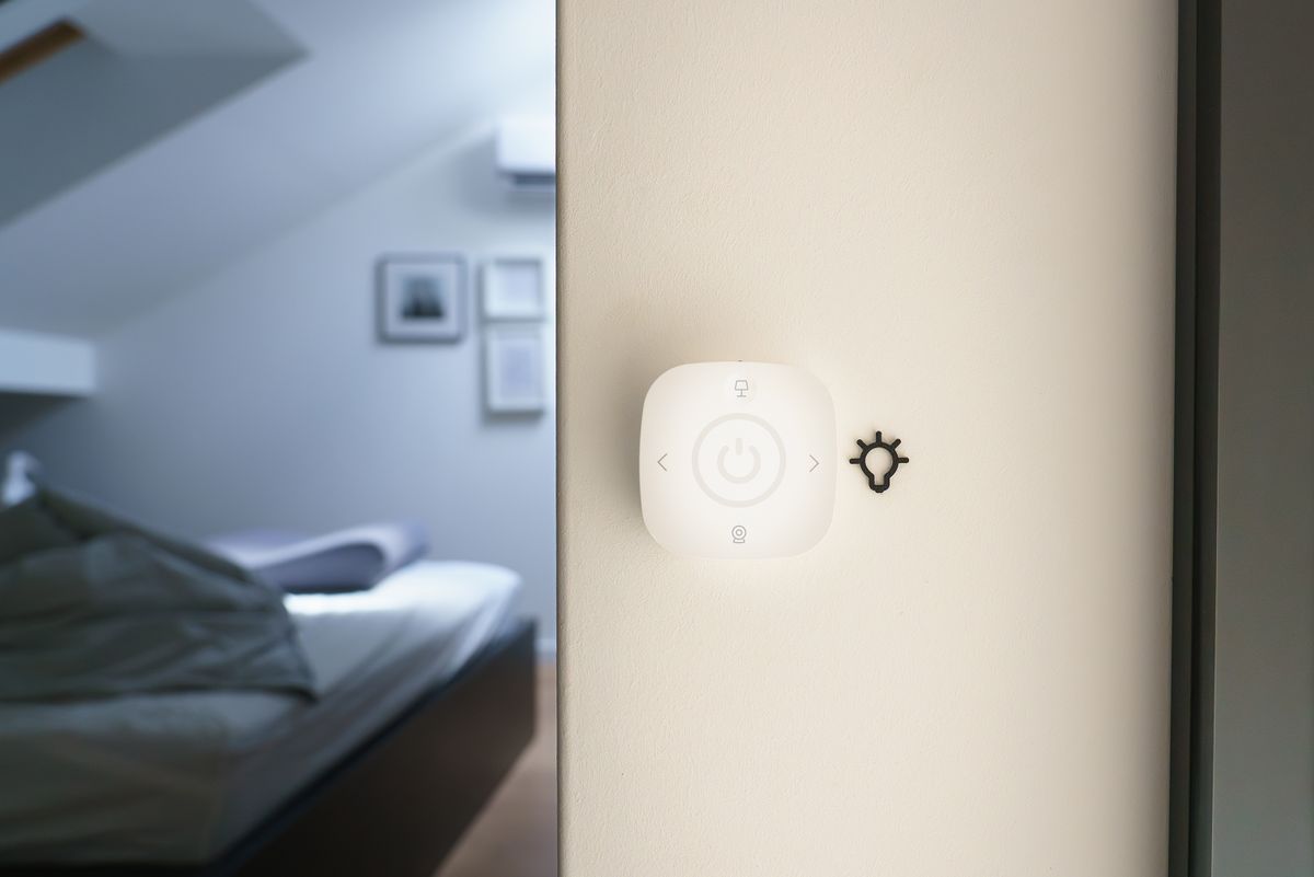 Interruptor inteligente blanco instalado junto a la puerta de un dormitorio