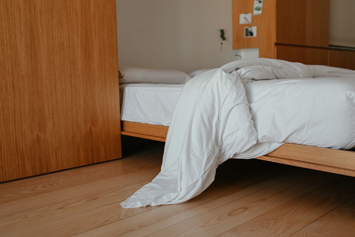 Cama acogedora con manta blanca gruesa y cabecero de madera