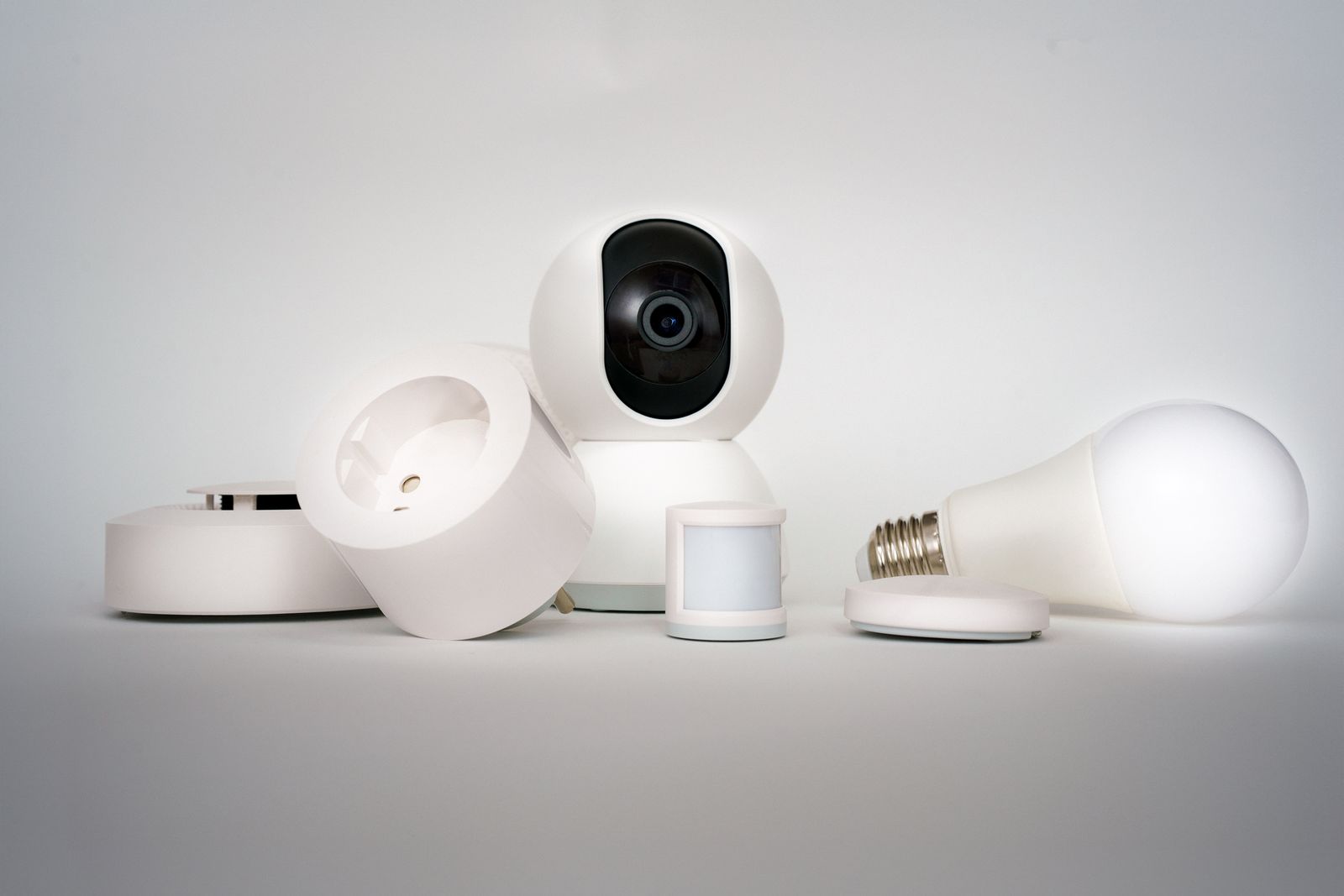 dispositivos de hogar conectado, camara, sensor de movimiento y enchufe inteligente sobre fondo blanco