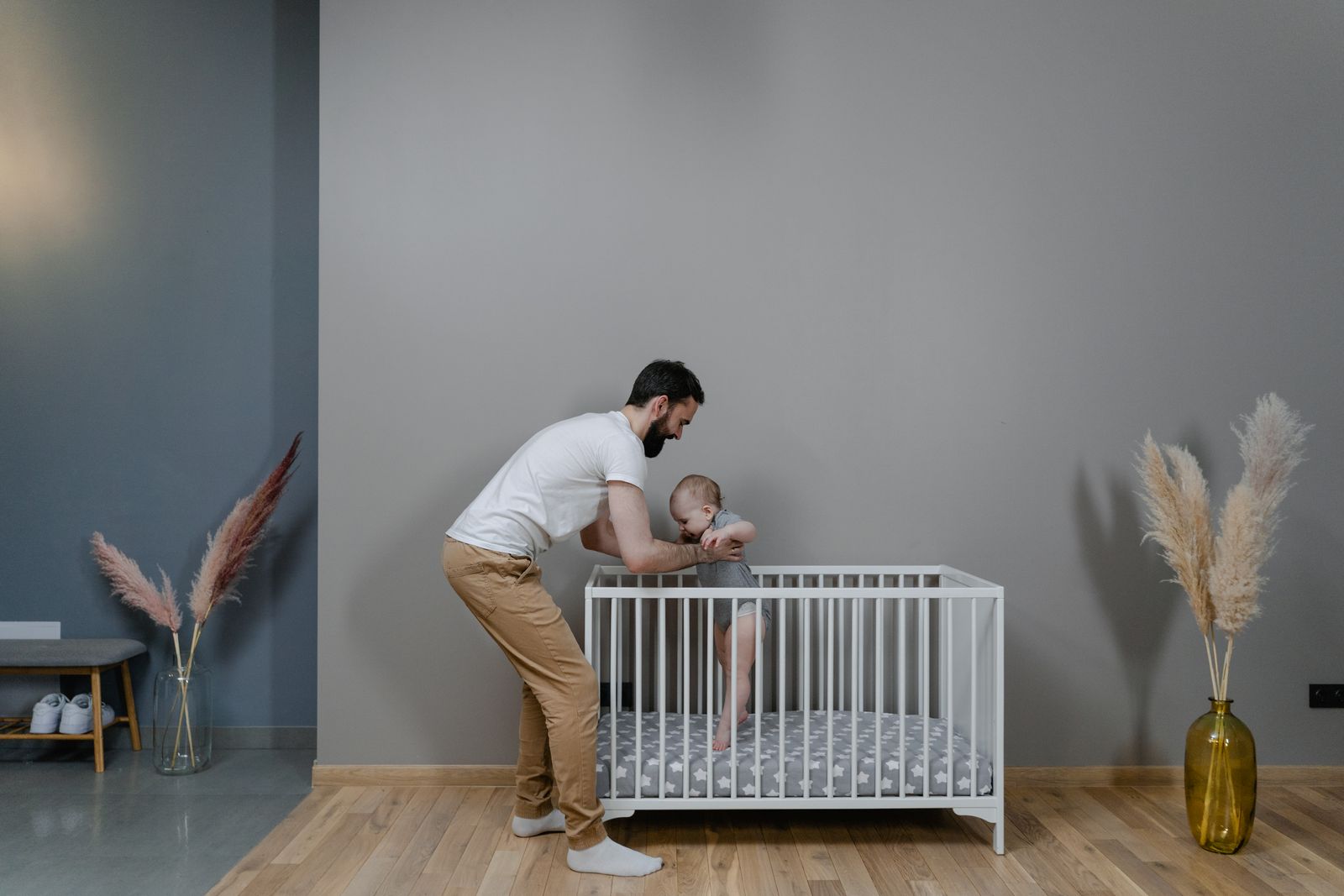 padre cargando a su bebé junto a la cuna
