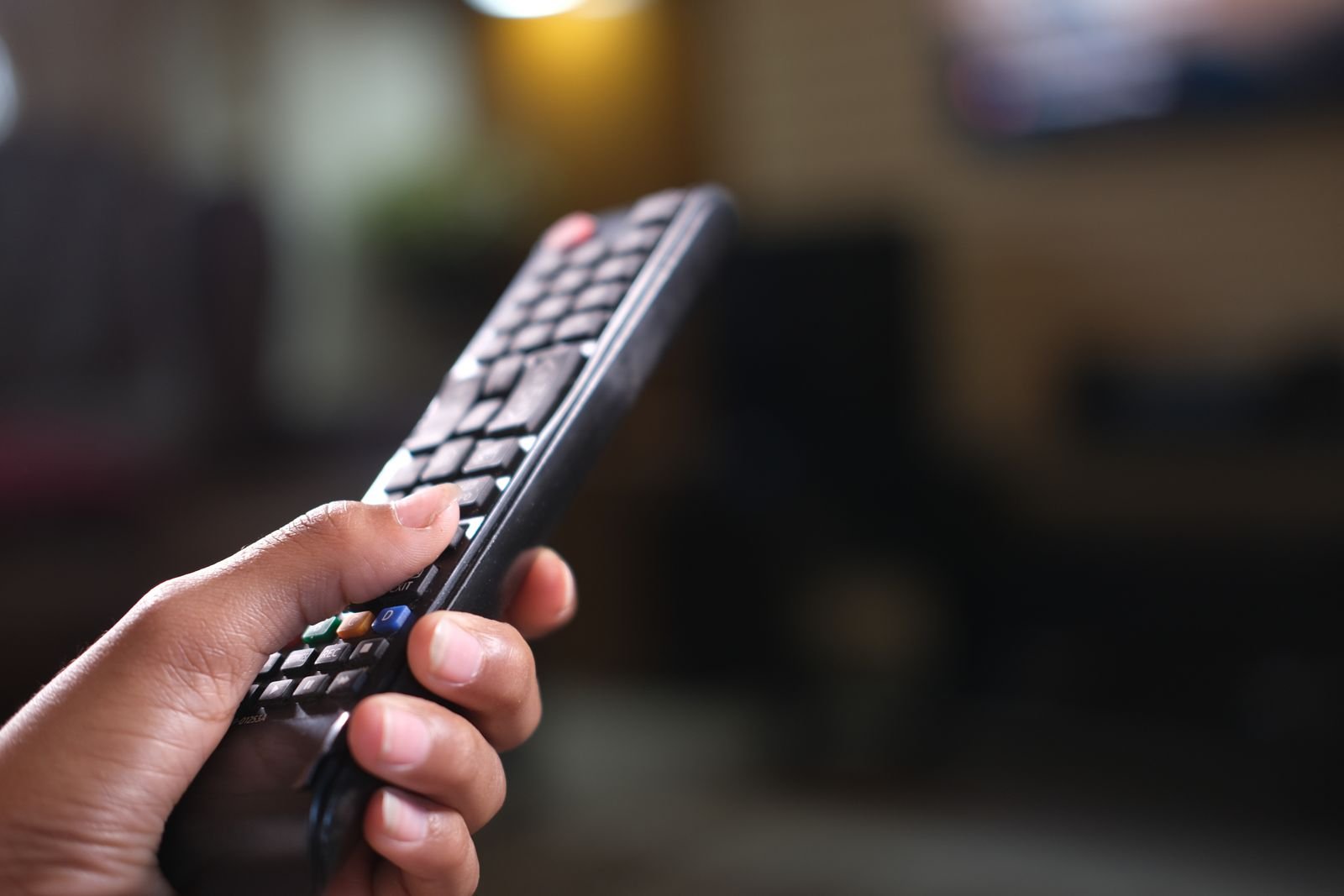 Mano sujetando un mando a distancia negro