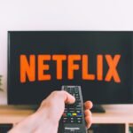 Persona sujetando un mando a distancia frente al televisor