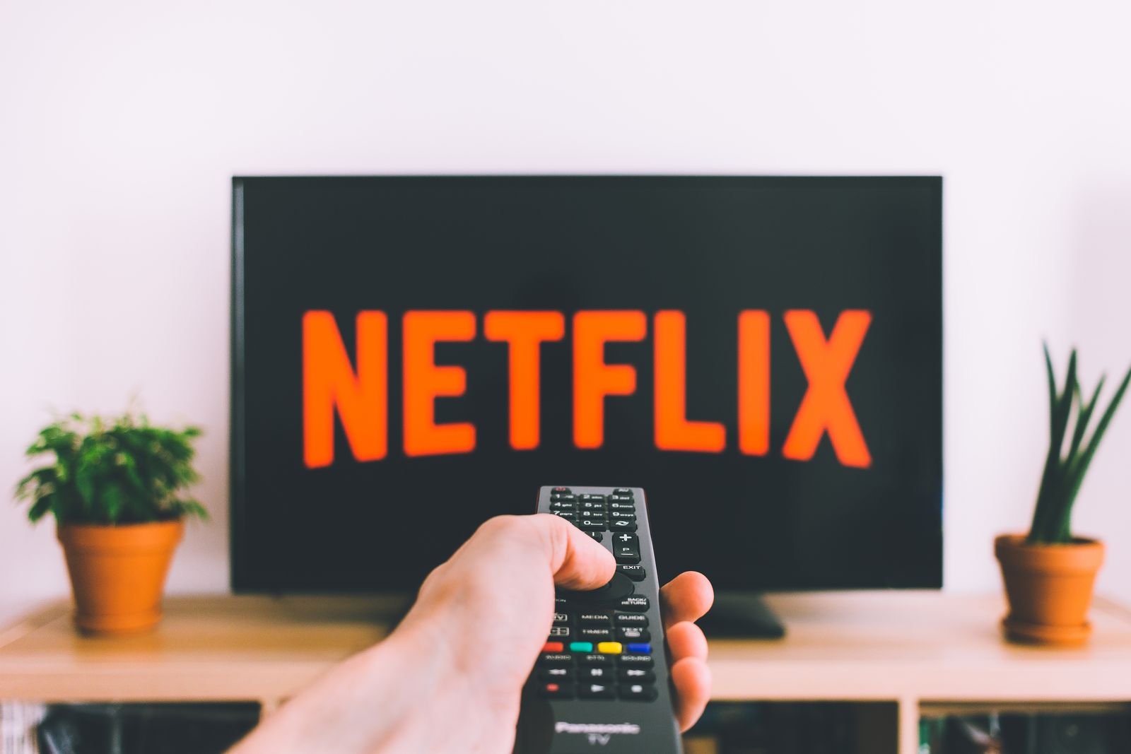 Persona sujetando un mando a distancia frente al televisor