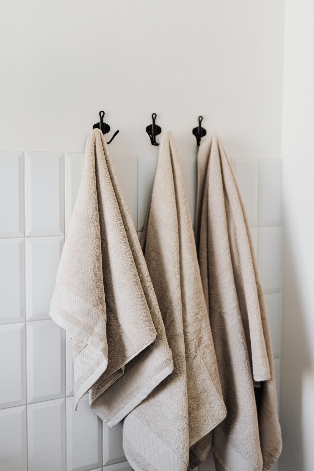 toallas beige colgadas en ganchos en un baño