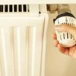 Mano ajustando la válvula termostática de un radiador