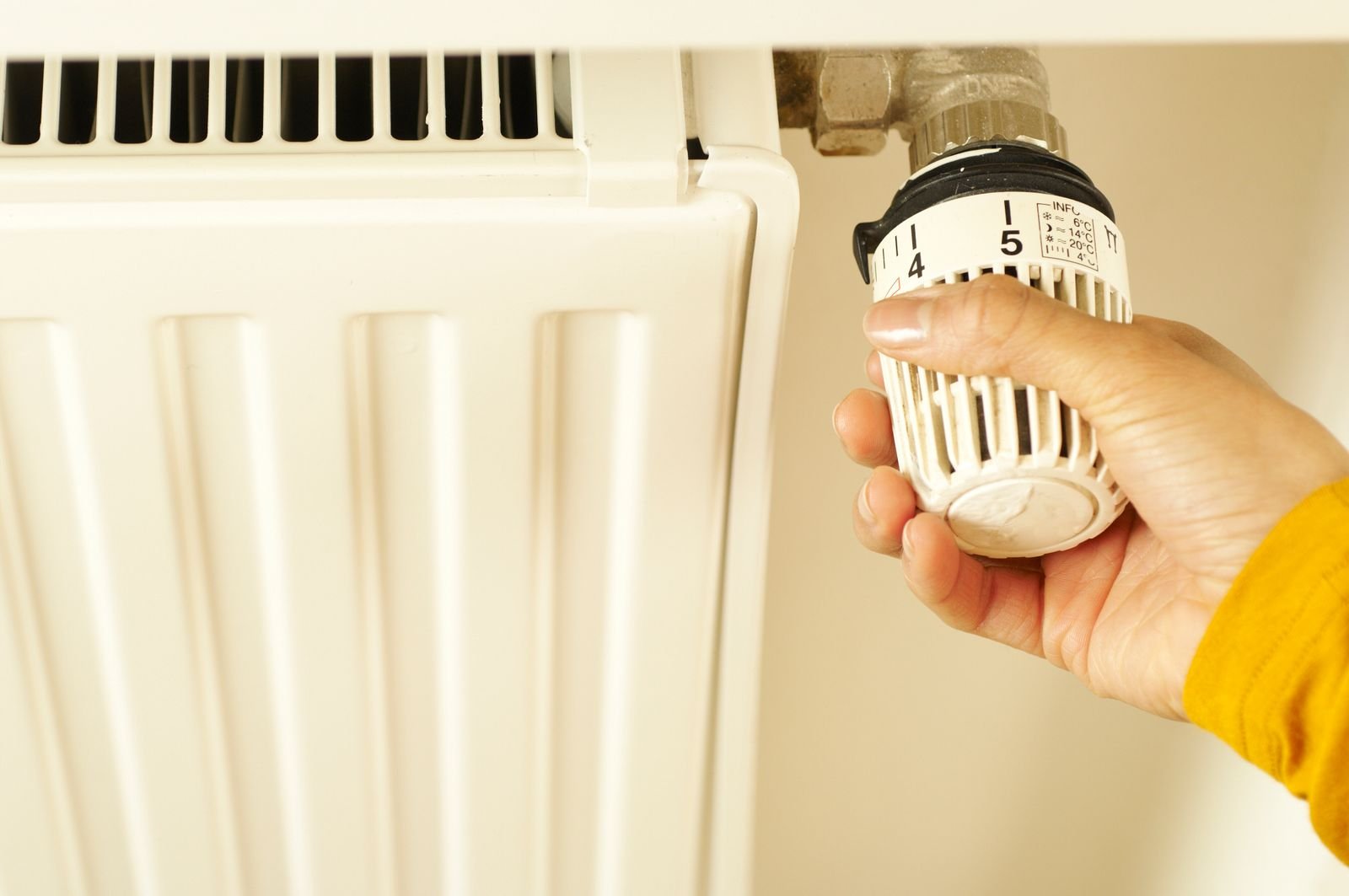 Mano ajustando la válvula termostática de un radiador