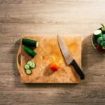 Cuchillo y verduras cortadas sobre una tabla de madera