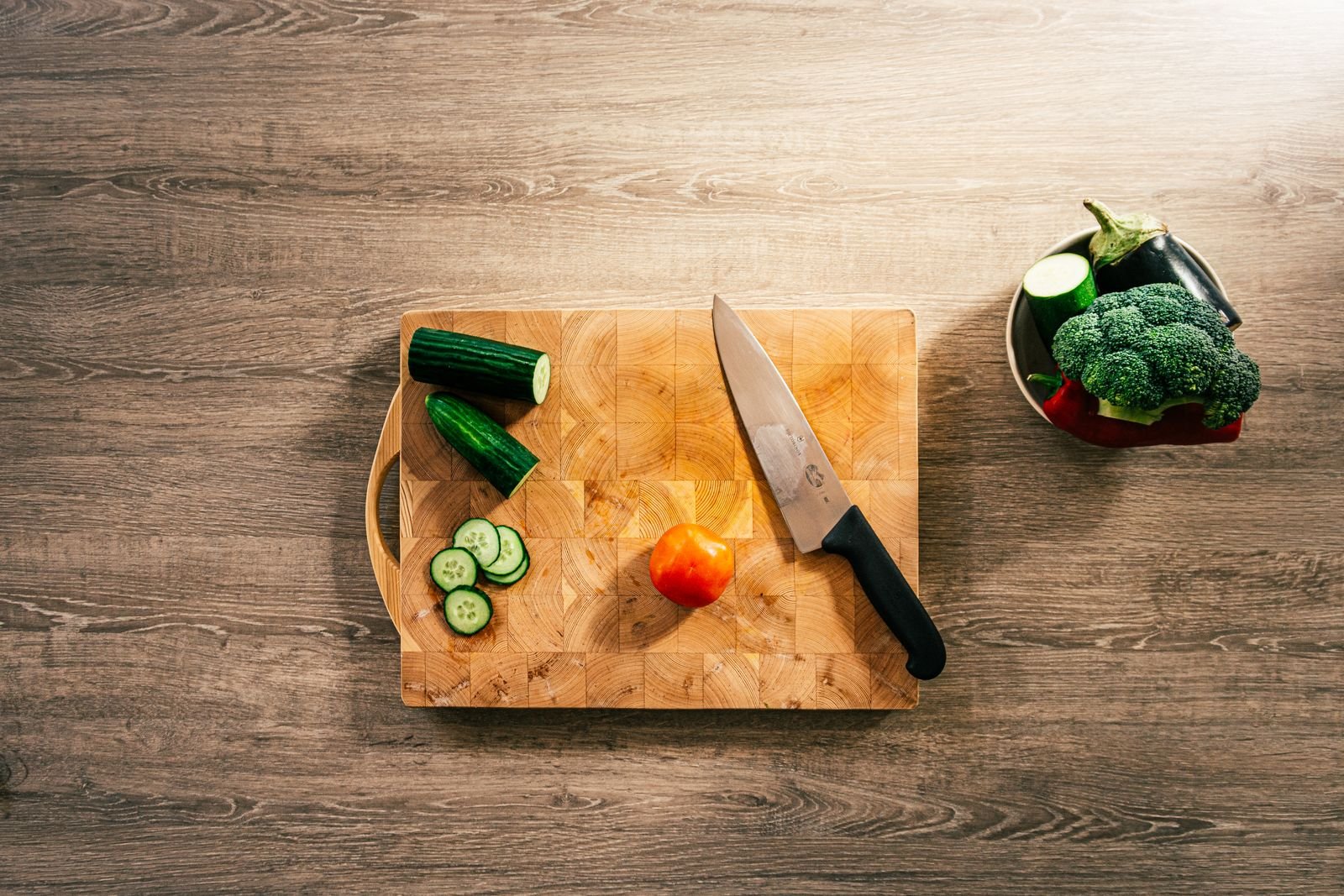 Cuchillo y verduras cortadas sobre una tabla de madera