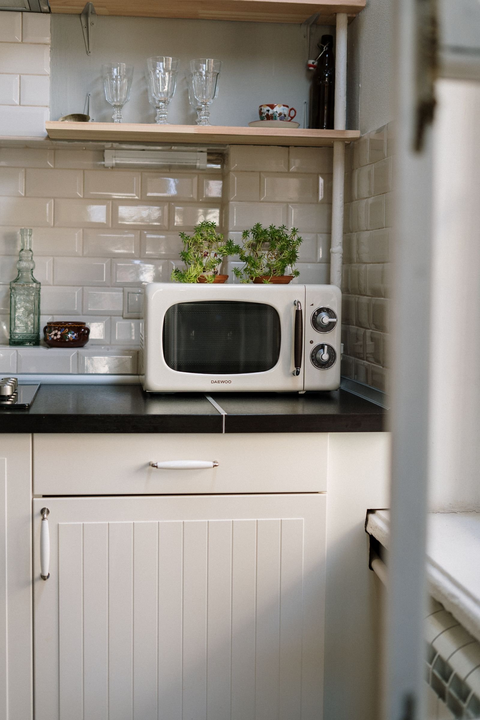 Microondas plateado sobre un mueble de cocina blanco