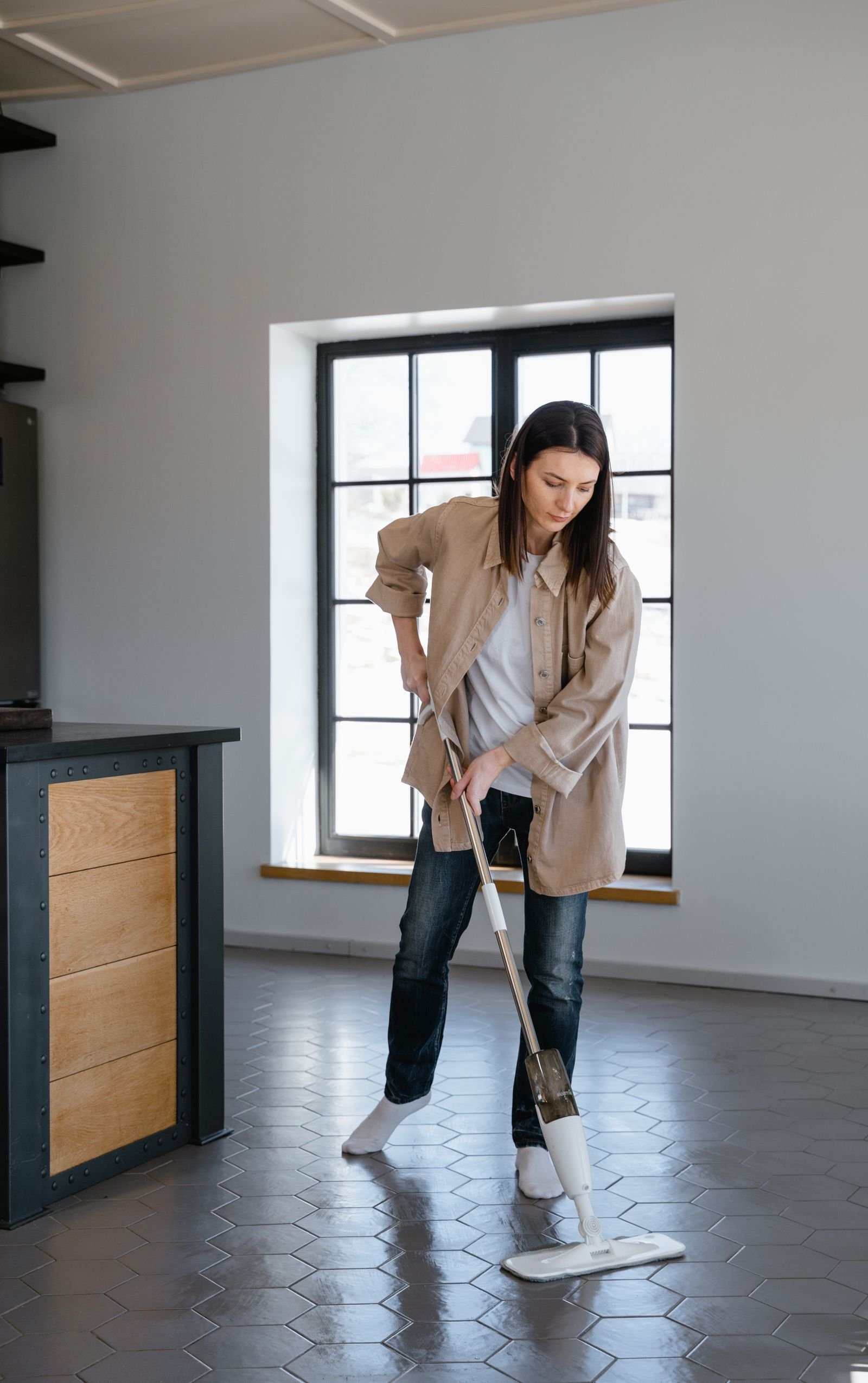 Persona fregando el suelo de una vivienda moderna con una mopa de vapor vertical