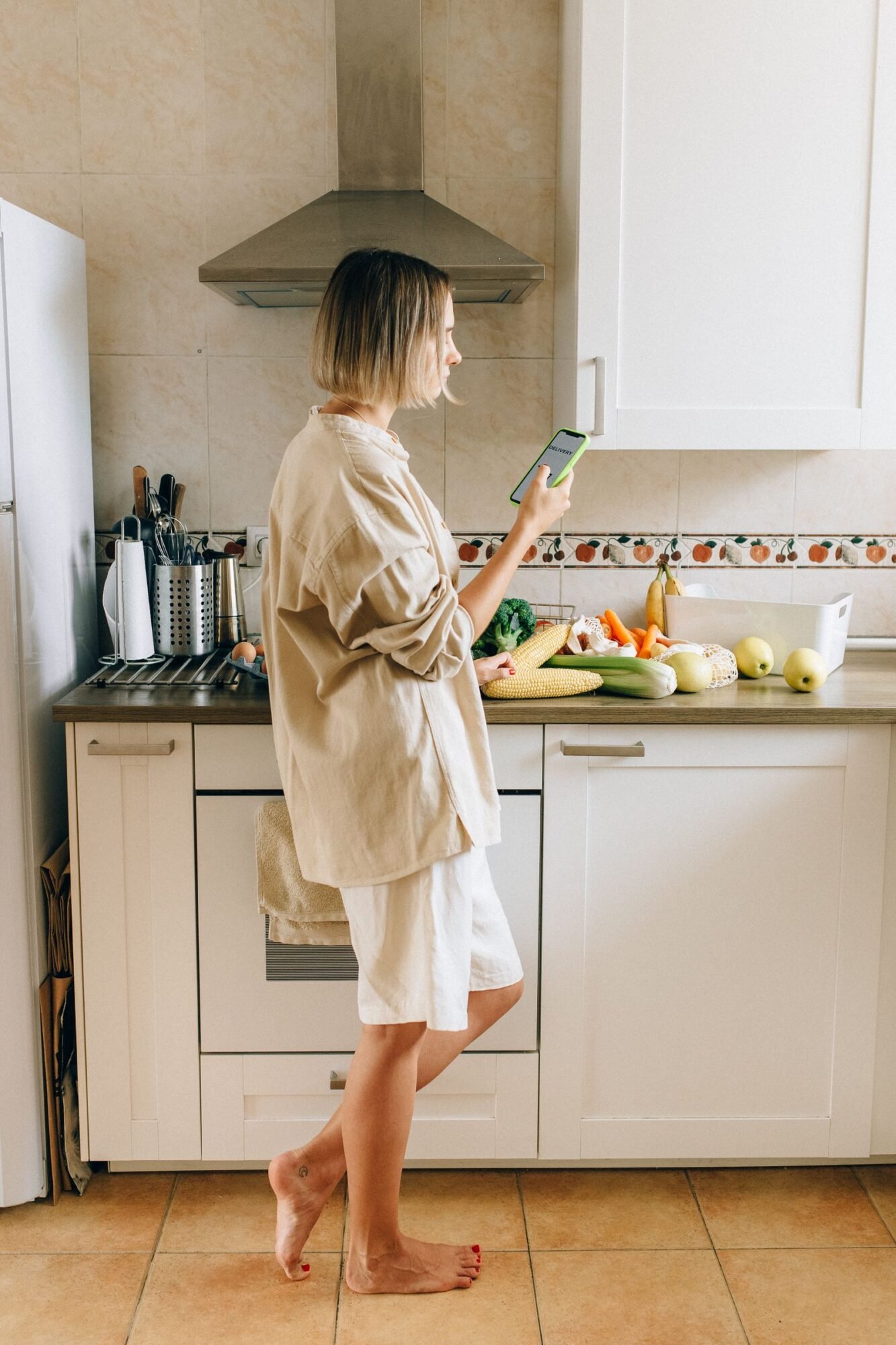 Persona usando el móvil en la cocina junto a la nevera