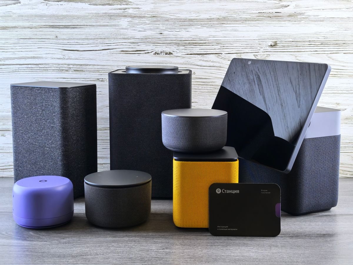 Varios altavoces inteligentes y una pantalla sobre una superficie de madera
