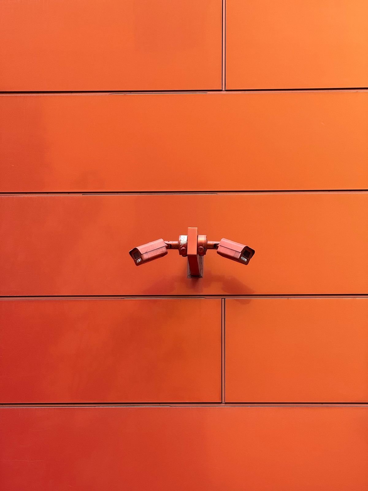 Dos cámaras de vigilancia montadas en una pared naranja