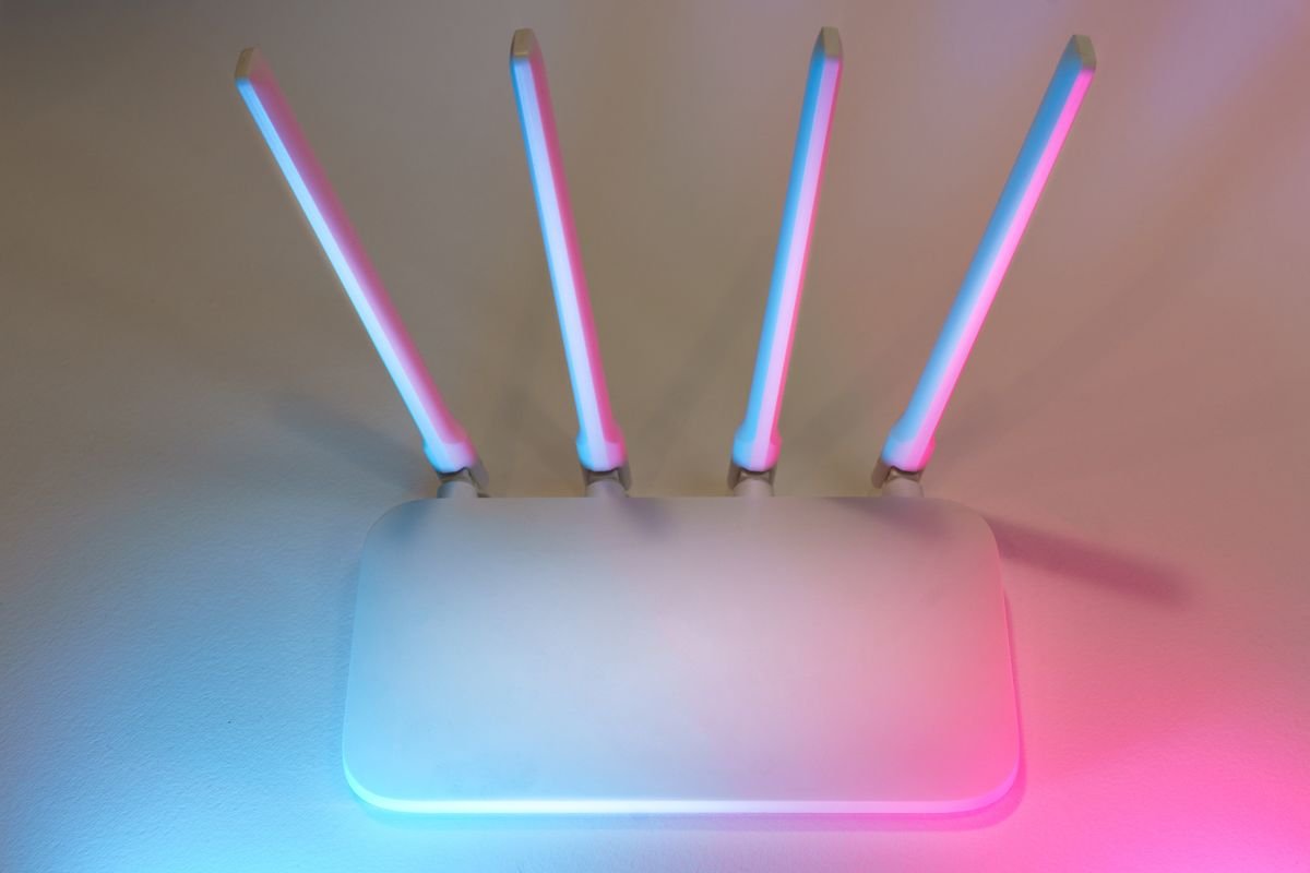 Router wifi blanco con antenas y luz azul y rosa