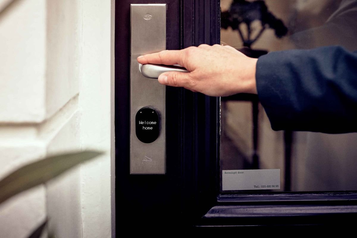 Mano abriendo una puerta con panel de acceso digital