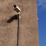 Cámara de seguridad exterior fijada a una pared de hormigón bajo un cielo azul