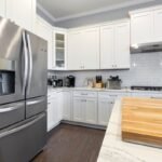 Cocina moderna con frigorífico de acero inoxidable y armarios blancos